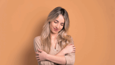 Woman smiling while holding herself, giving herself a hug.
