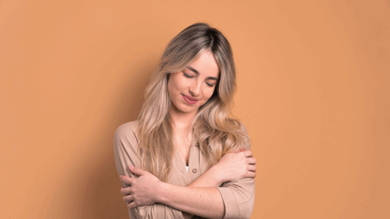 Woman smiling while holding herself, giving herself a hug.