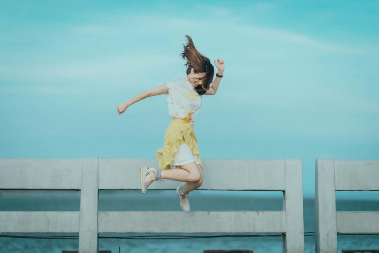 Happy woman jumping in the air on the pier.
