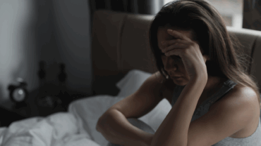 Woman is sad and depressed sitting in her bed.