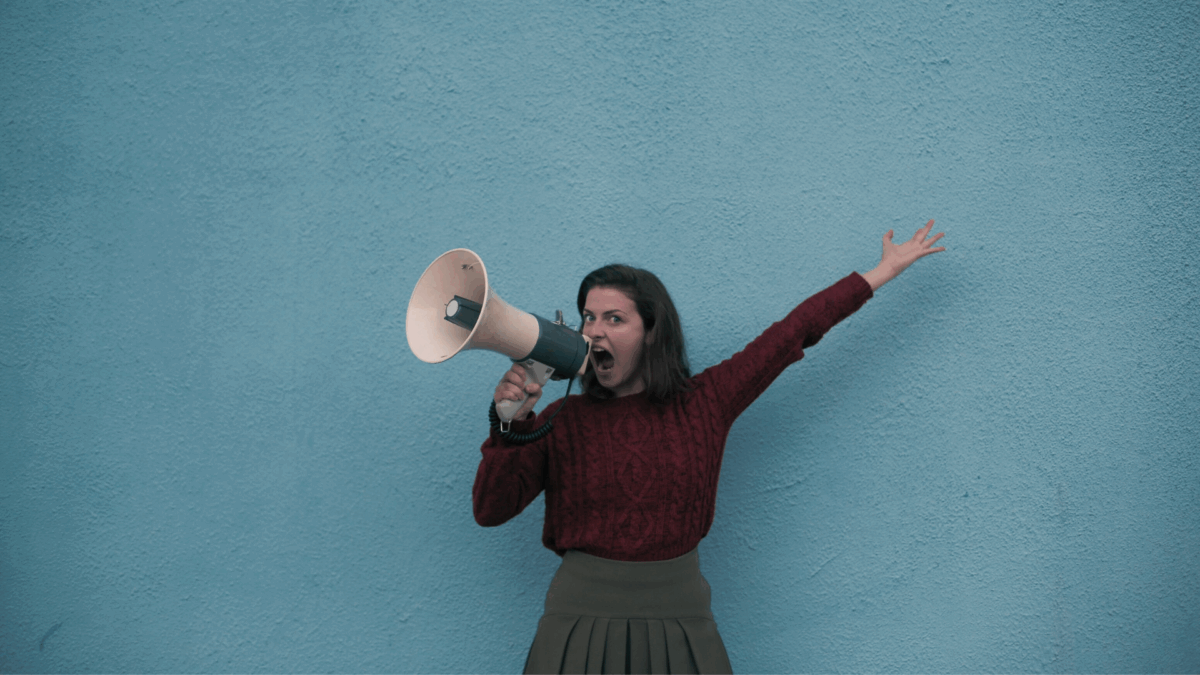 Woman holding a large bullhorn yelling into it.