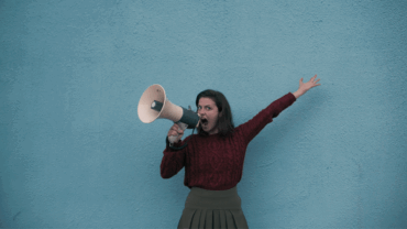 Woman holding a large bullhorn yelling into it.