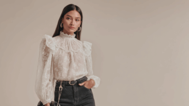 Beautiful and confident young woman modelling in a white lace blouse and black jeans.
