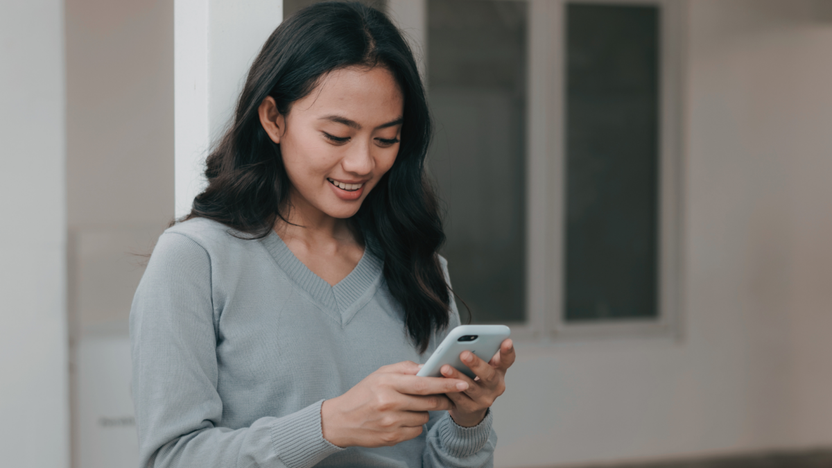 Young woman smiling while looking at a text from a man she has been dating