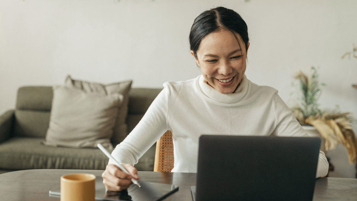 Woman smiling while writing in a digital anxiety journal at her desk